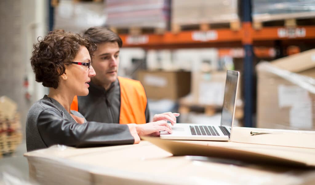 Woman and man looking at laptop computer in warehouse