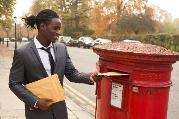 A business man drops off two envelopes at the post office.